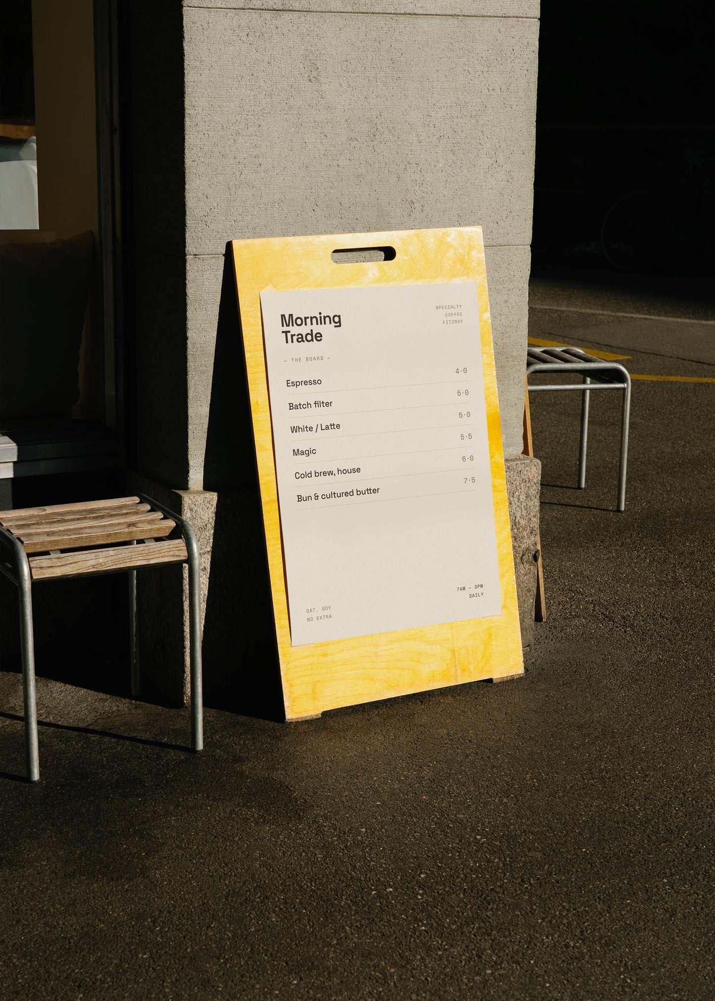 Yellow a-frame sign with a menu on a gray floor against a wall.